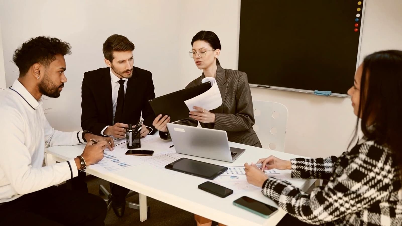 A team around a meeting table with laptops and documents